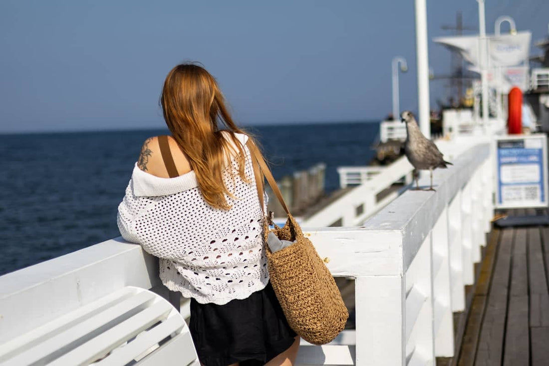 A woman sitting on a bench looking out at the ocean