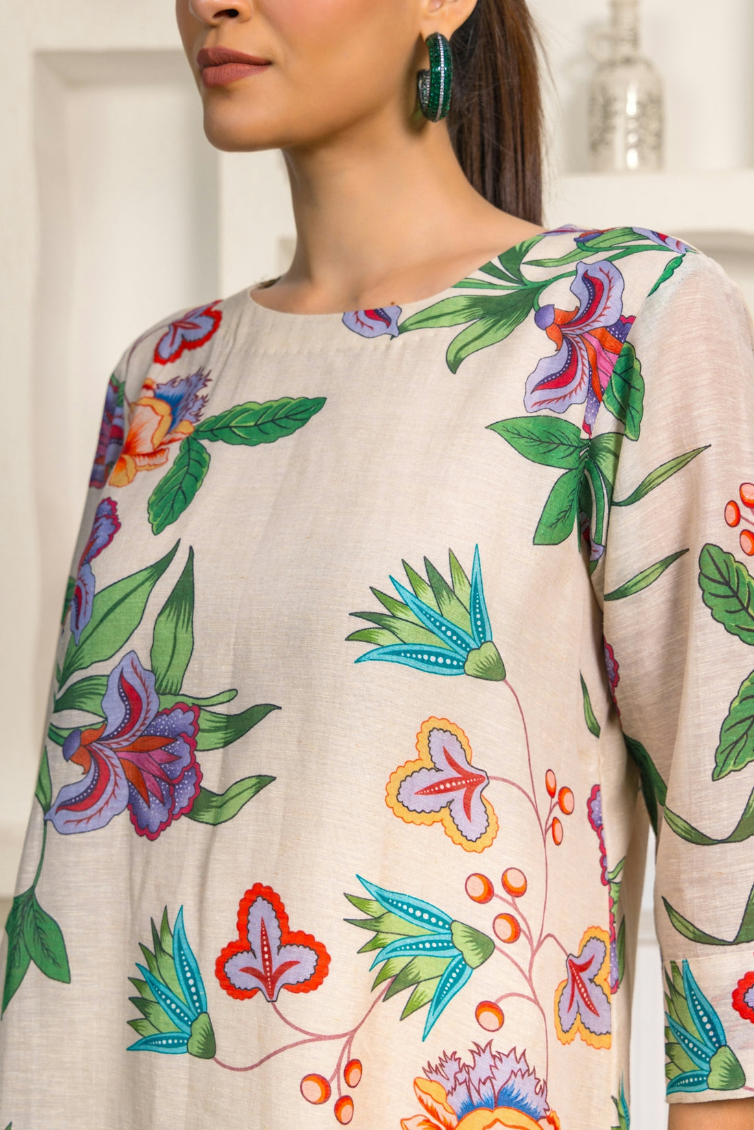 A woman wearing a flowered top and a pair of earrings