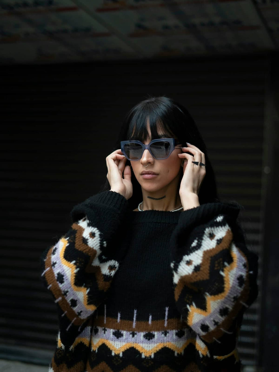 A woman in a black and brown sweater and sunglasses