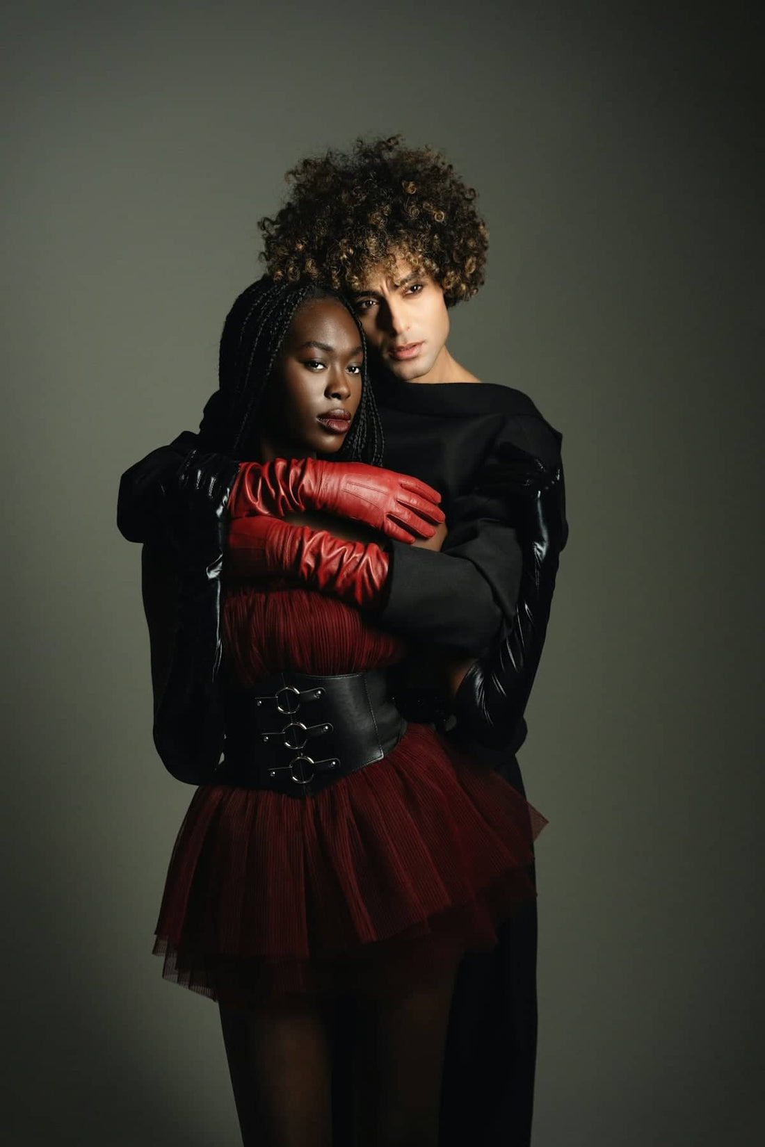 Two fashionable people embrace in a studio portrait.