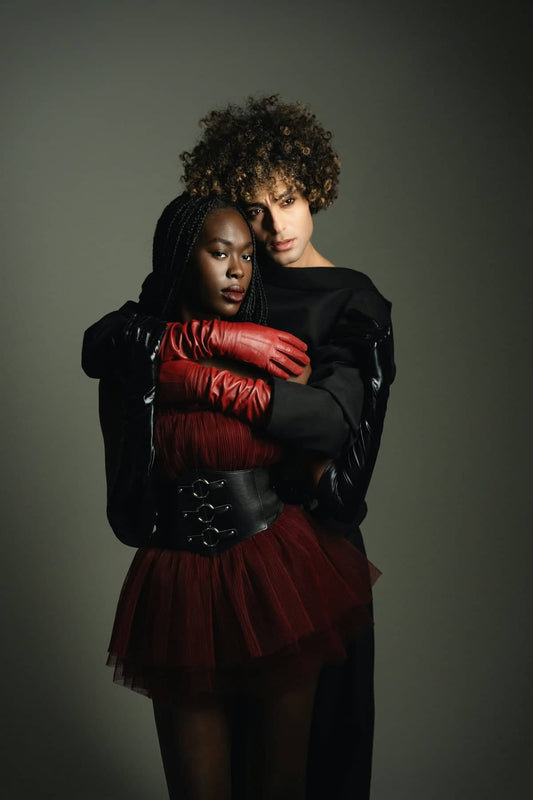 Two fashionable people embrace in a studio portrait.
