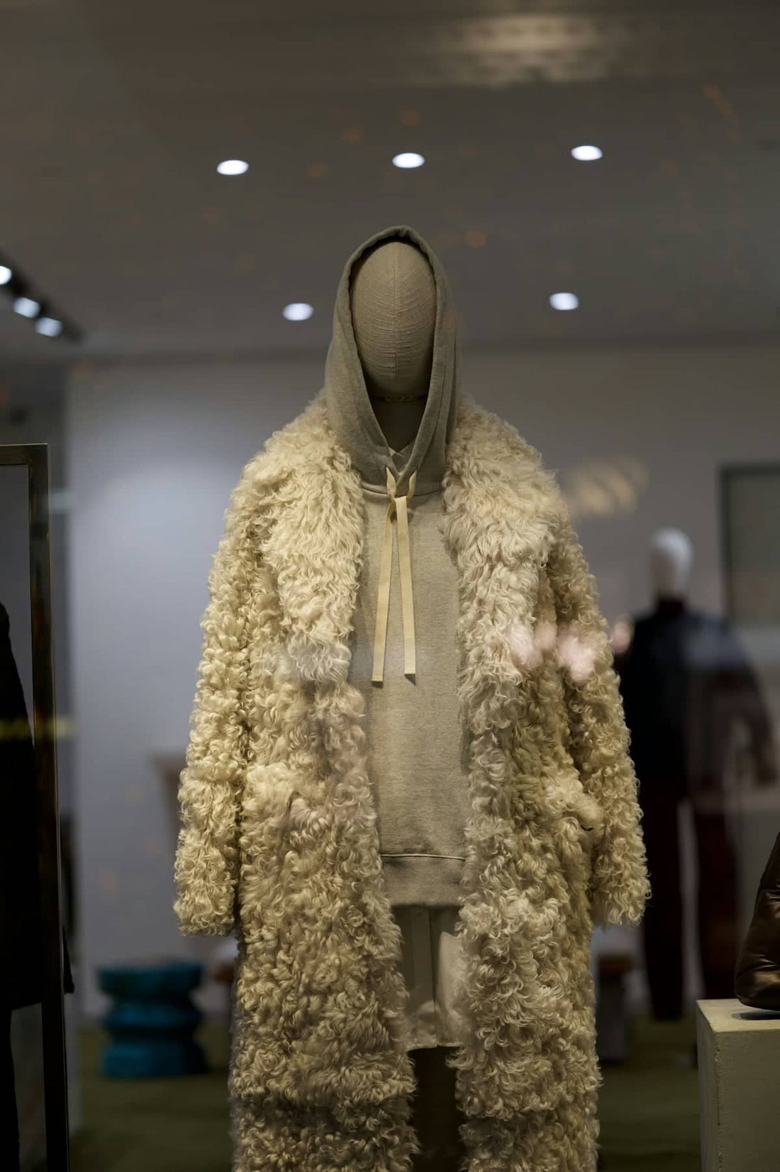 A mannequin displays fashion inside a shop window.