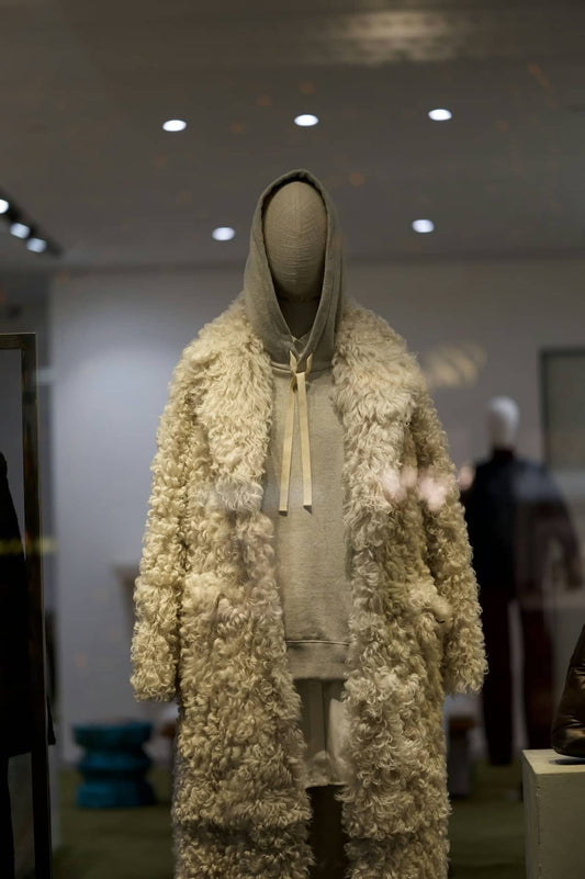A mannequin displays fashion inside a shop window.