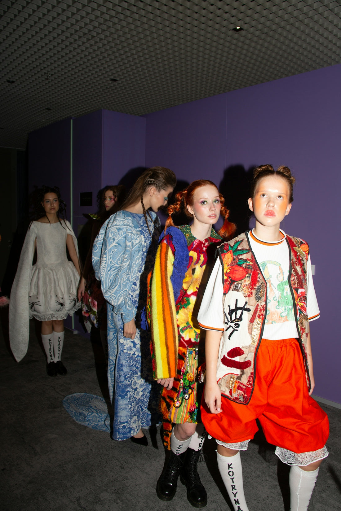 Fashion models lined up backstage, waiting.