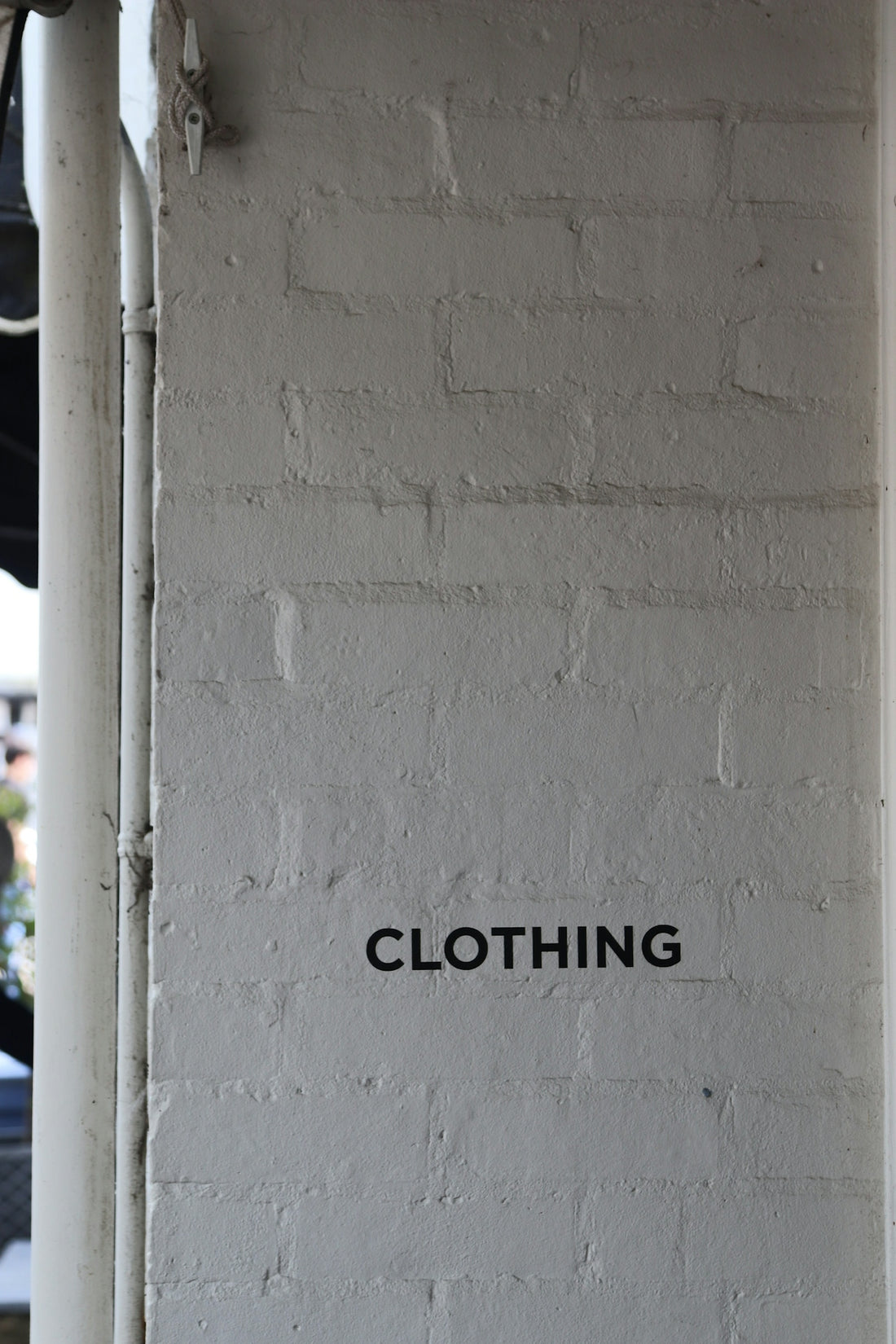 The word clothing is on a brick wall.