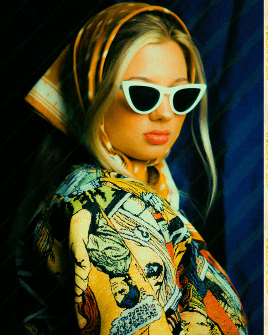 Woman with scarf and sunglasses wears patterned jacket