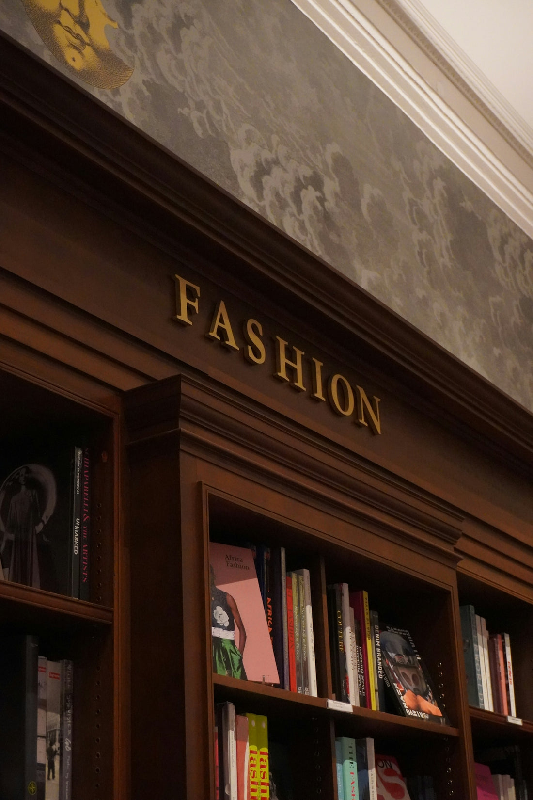 Golden letters spell fashion above bookshelves