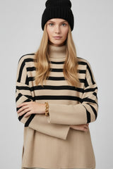 Pull beige oversize à col roulé avec rayures noires et fentes sur les côtés