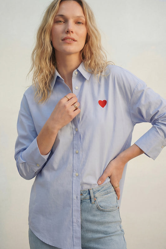 Q2 blue oxford cotton shirt with embroidered red heart detail worn by a model with light jeans