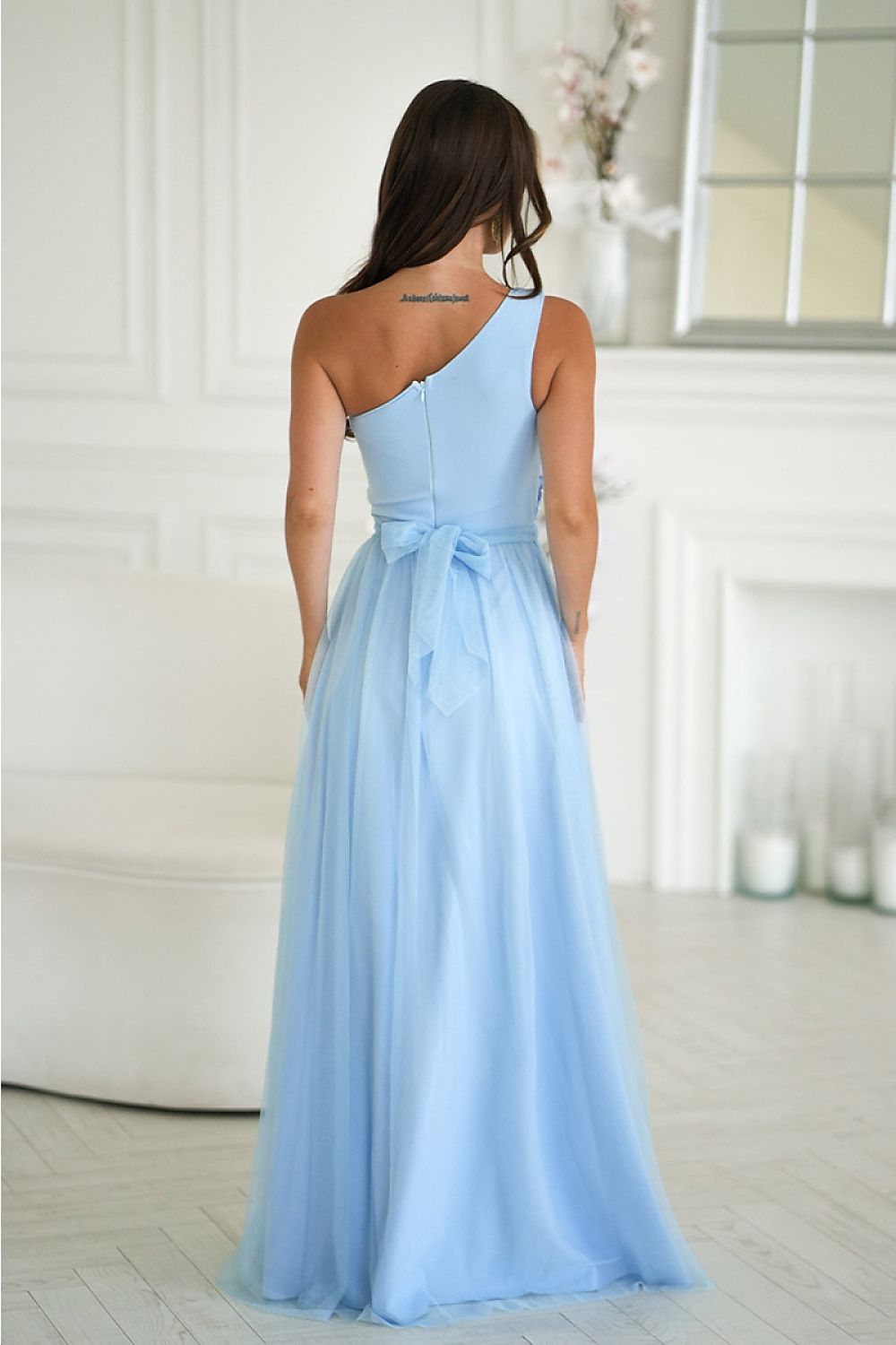Back view of a light blue elegant one-shoulder dress with a bow detail for special occasions