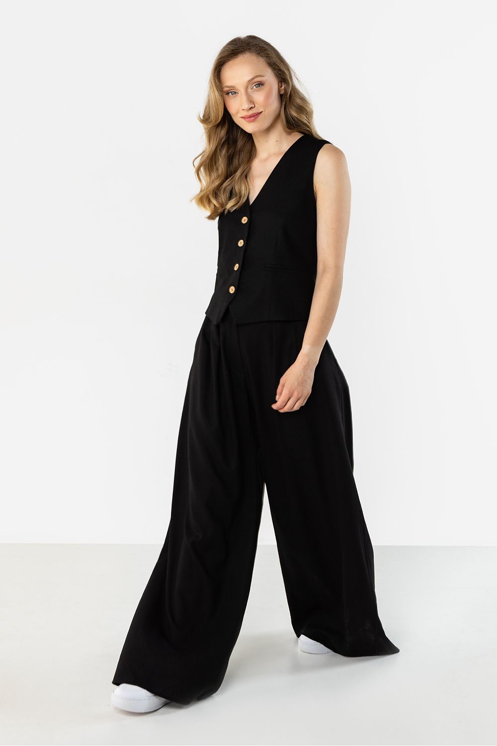 Awama black gilet with button detailing, paired with wide-leg trousers for a stylish look