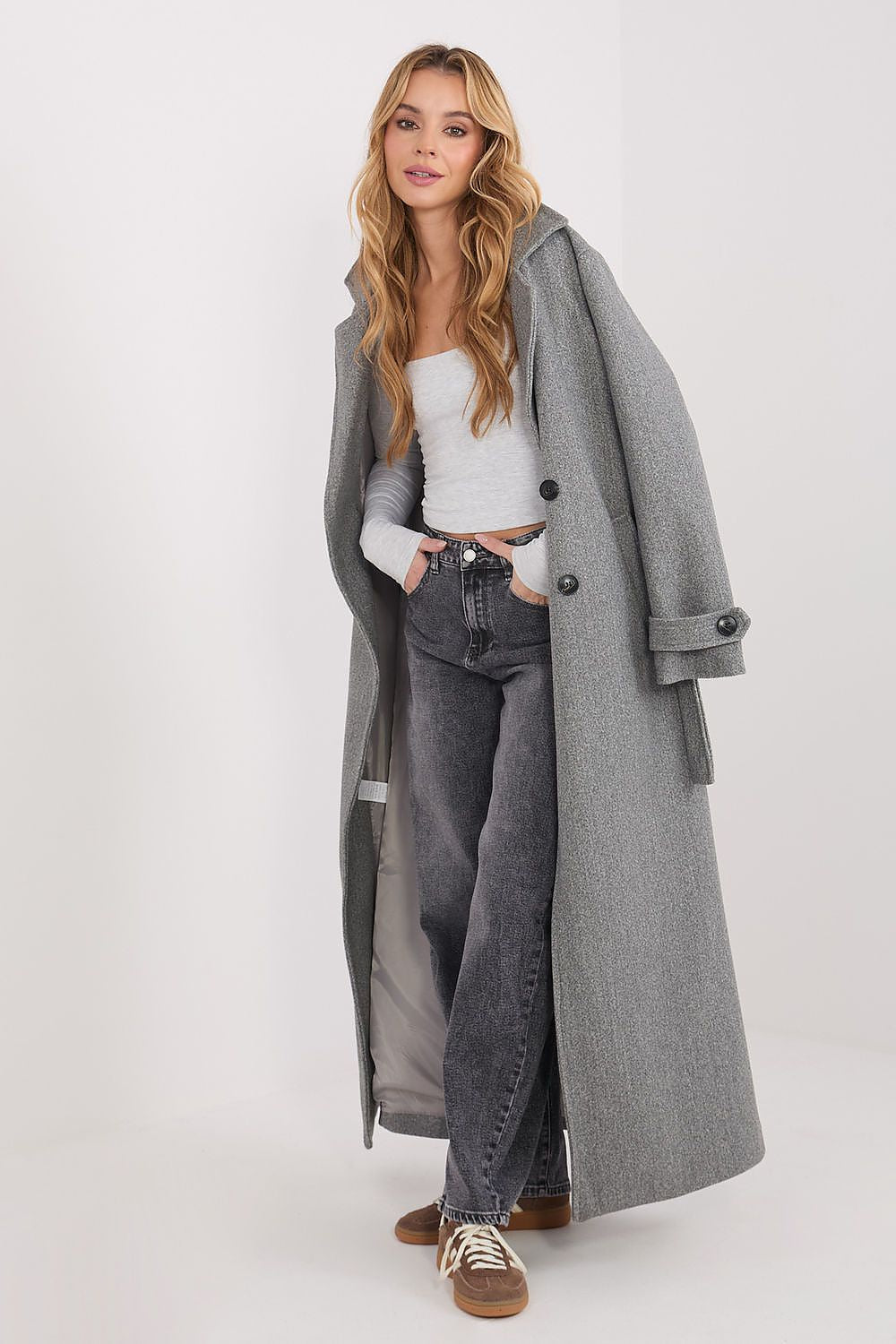 Stylish model wearing a trendy square neckline blouse paired with a long grey coat and black jeans