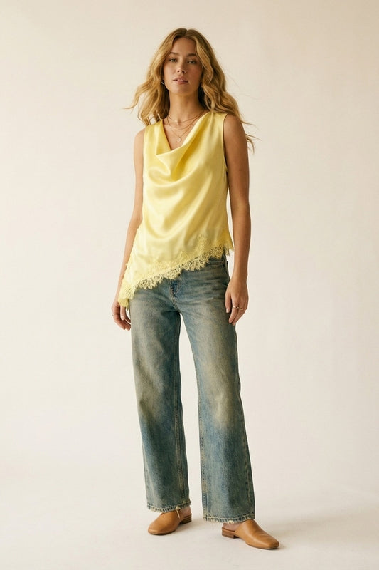 Stylish model wearing a yellow satin sleeveless top with lace trim paired with jeans